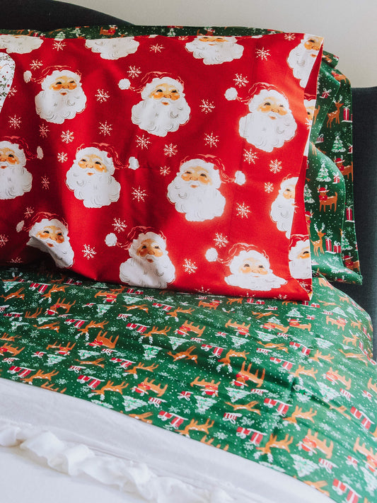 Reindeer printed sheets shown on made up bed. Red Santa pillow case on pillow. 