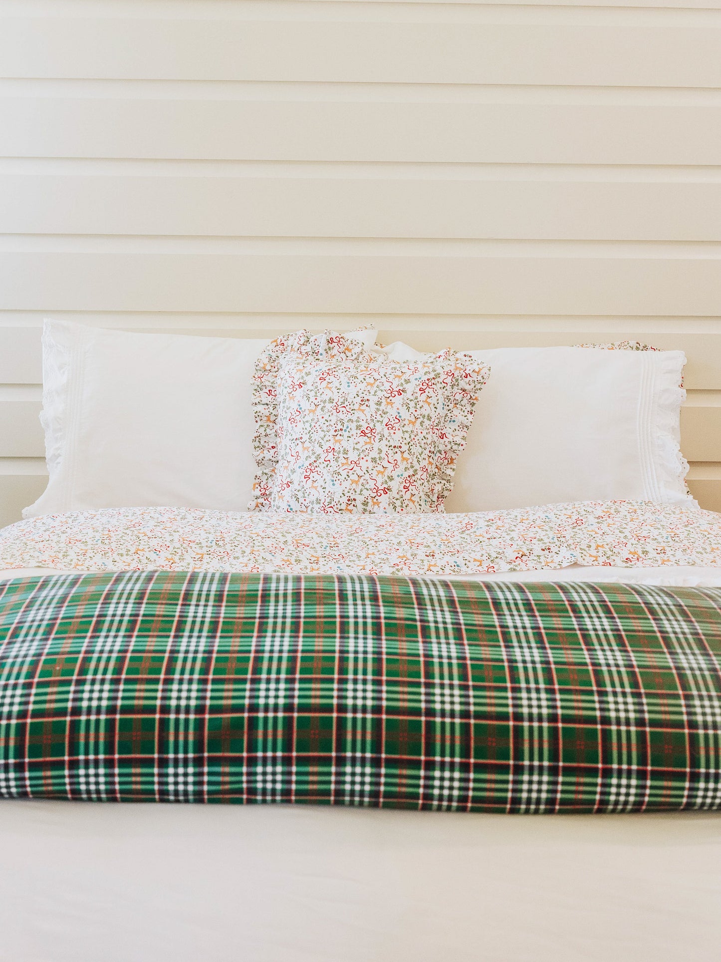 Holiday themed bed made with traditional green plaid folded duvet at end of bed. 