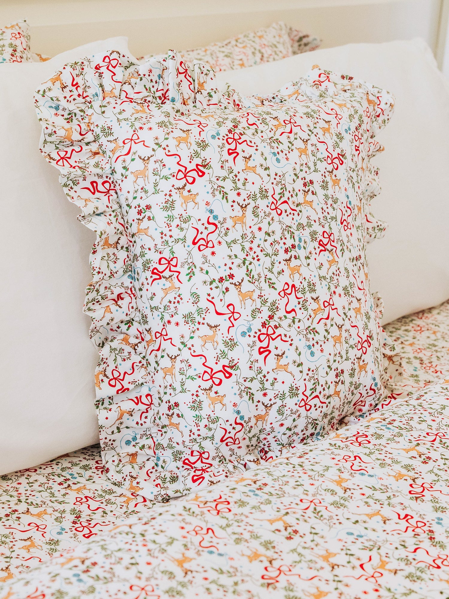 Christmas themed pillow shown with matching themed sheets. 
