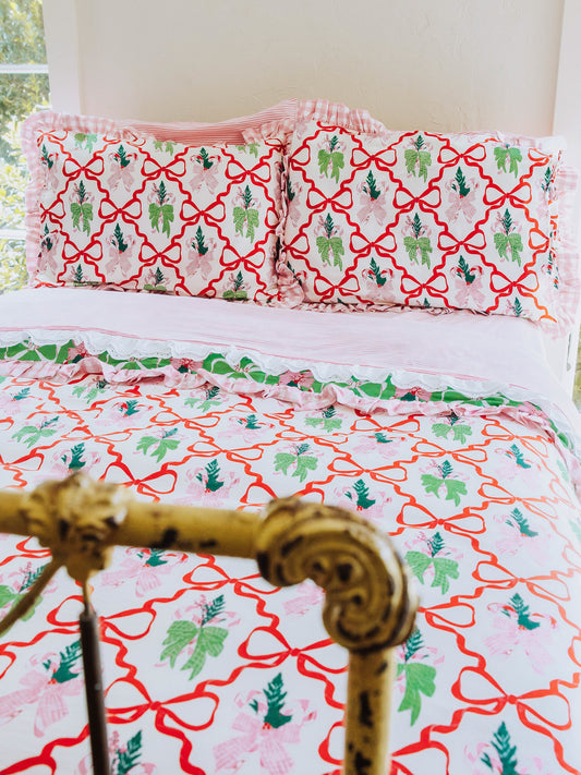 Christmas themed bedding shown with pink lace trimmed sheets. 