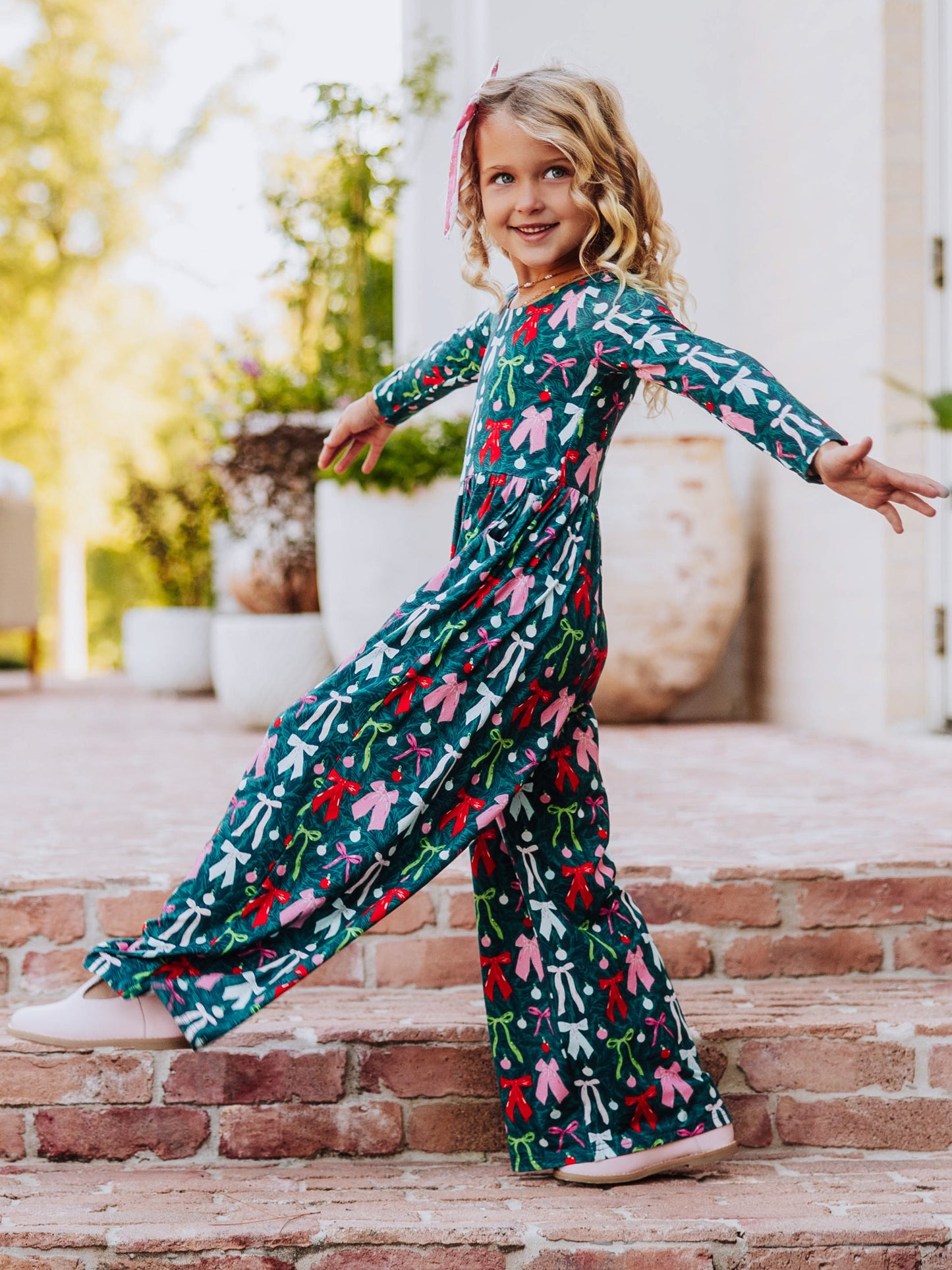 Model kicking out foot wearing a multi-colored bow leggy romper. 