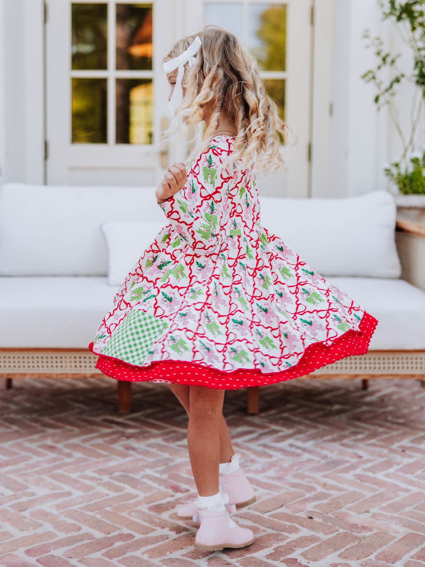 Girl twirling in her holiday themed dress that is double skirted. 