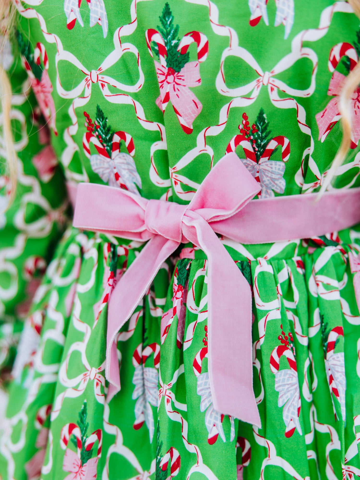 Up close shot of pink velvet tie on back of green holiday themed dress.