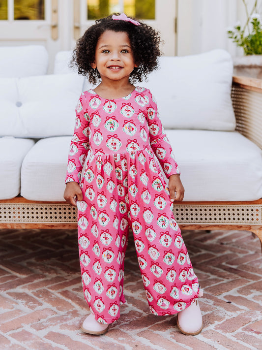 Girl standing in front of white couch wearing a pink nutcracker printed leggy romper.