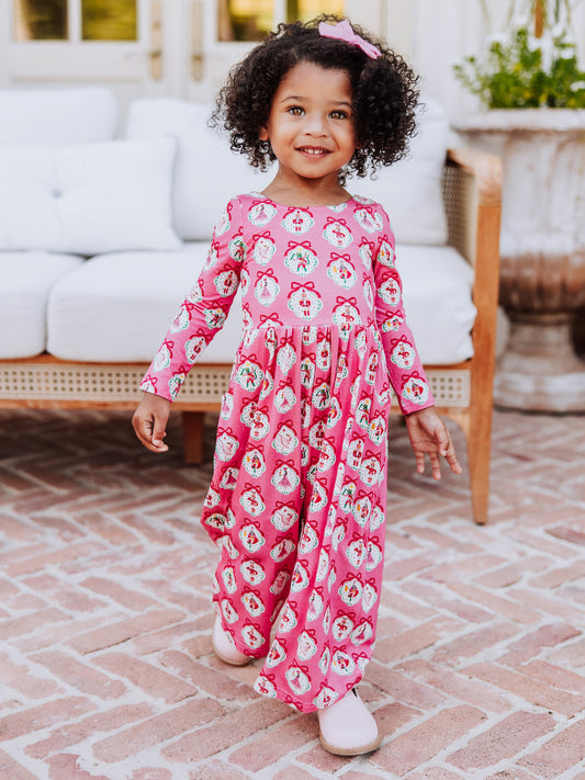 Girl standing in front of white couch wearing a pink nutcracker printed leggy romper.