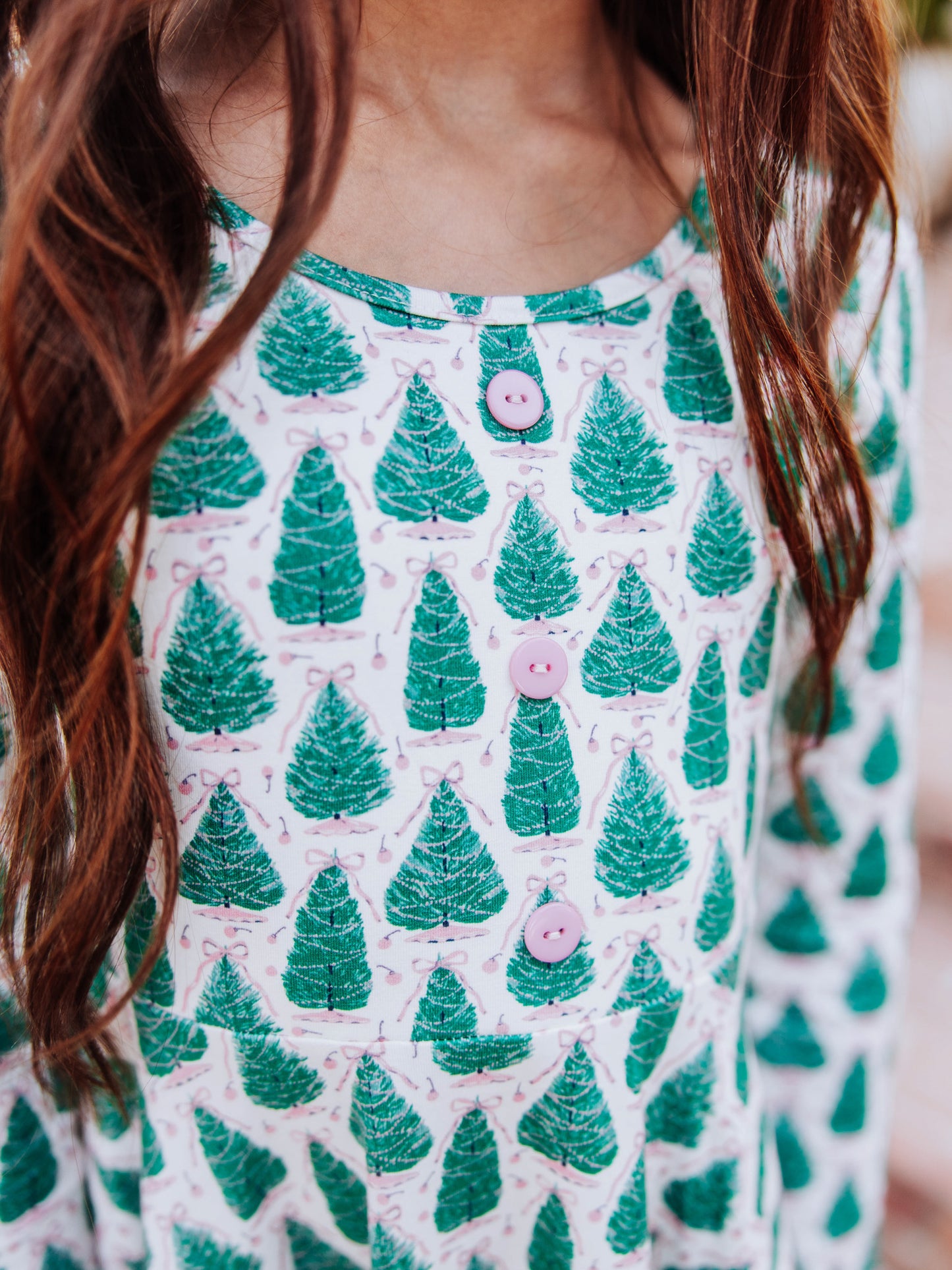 Up close picture of accent buttons on bodice of tree dress with bows on top. 