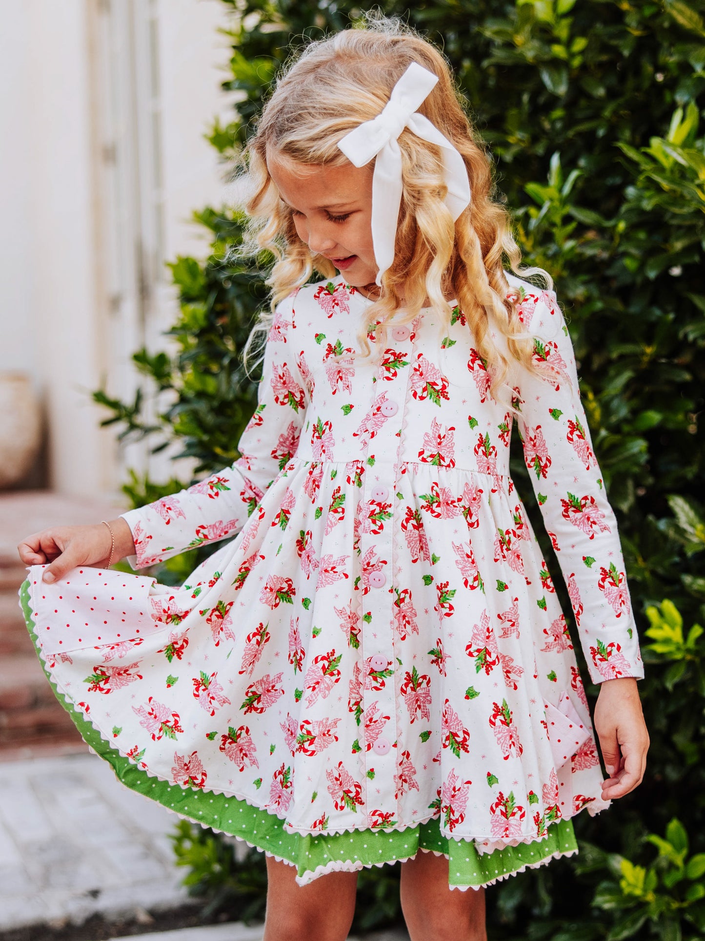 Model is holding the side of her double skirted holiday themed dress. 