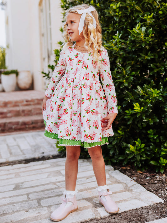 Girl is standing outside wearing a holiday themed dress. 