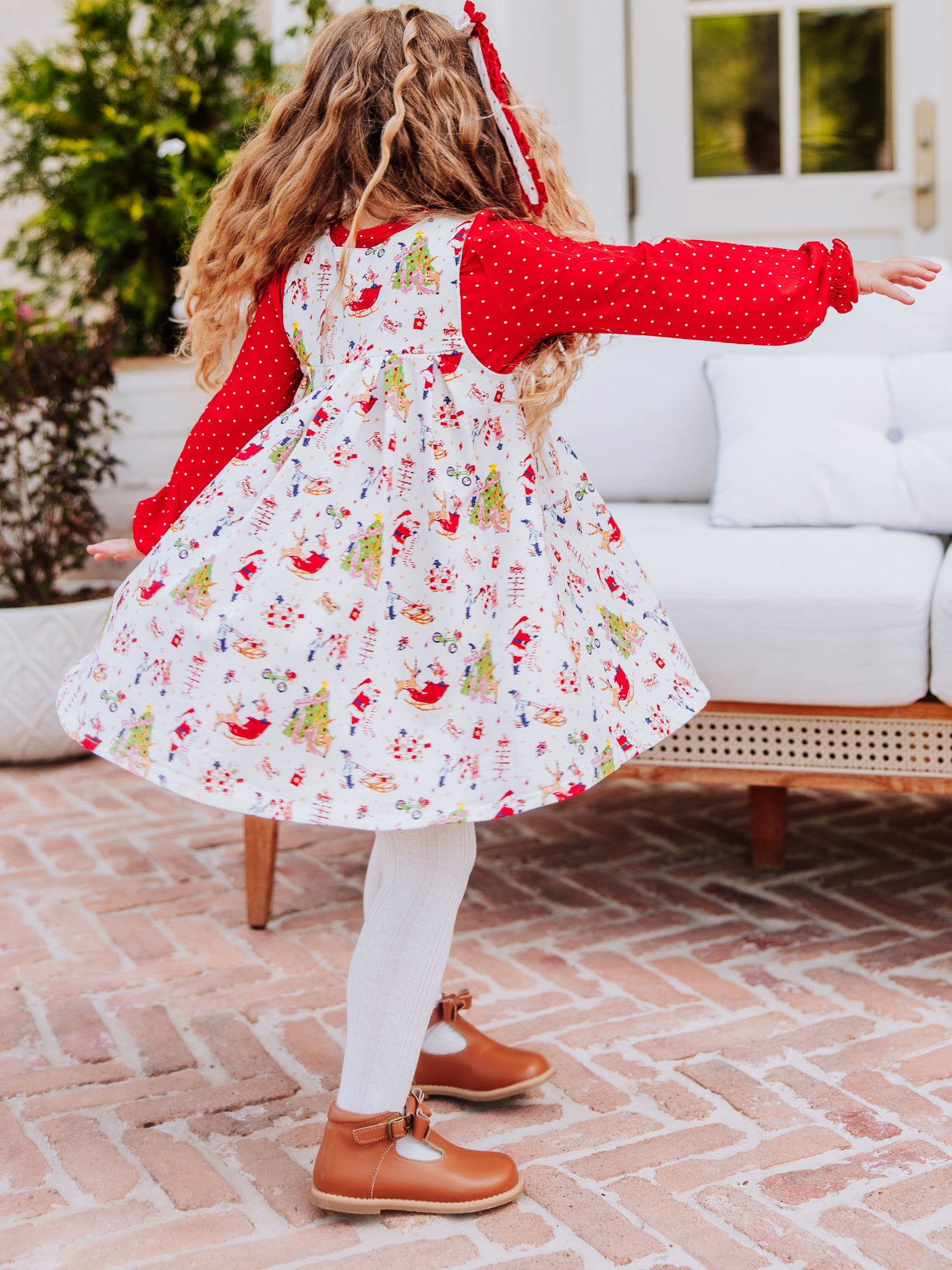 Girl is spinning slowly in a holiday themed retro jumper. Girl has on white tights and brown buckle shoes. 