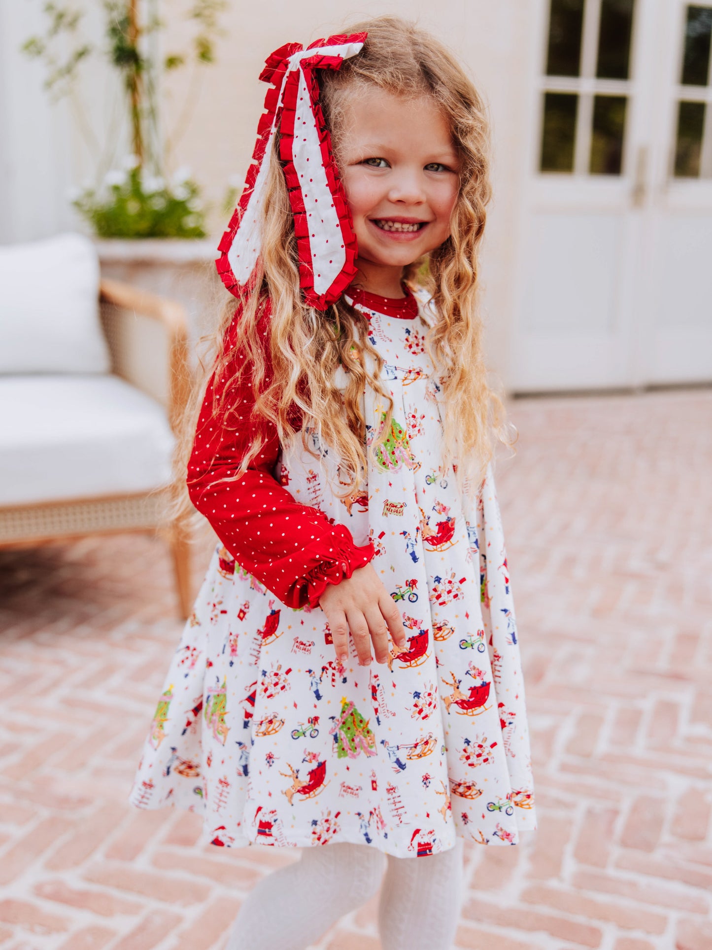 Girl wearing a holiday themed retro jumper and has a bow on