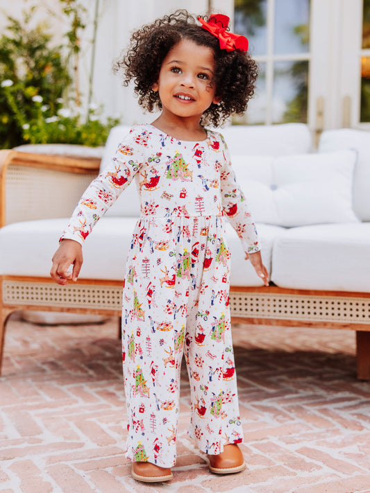 Model wearing a north pole printed leggy romper white standing in front of a white couch. 