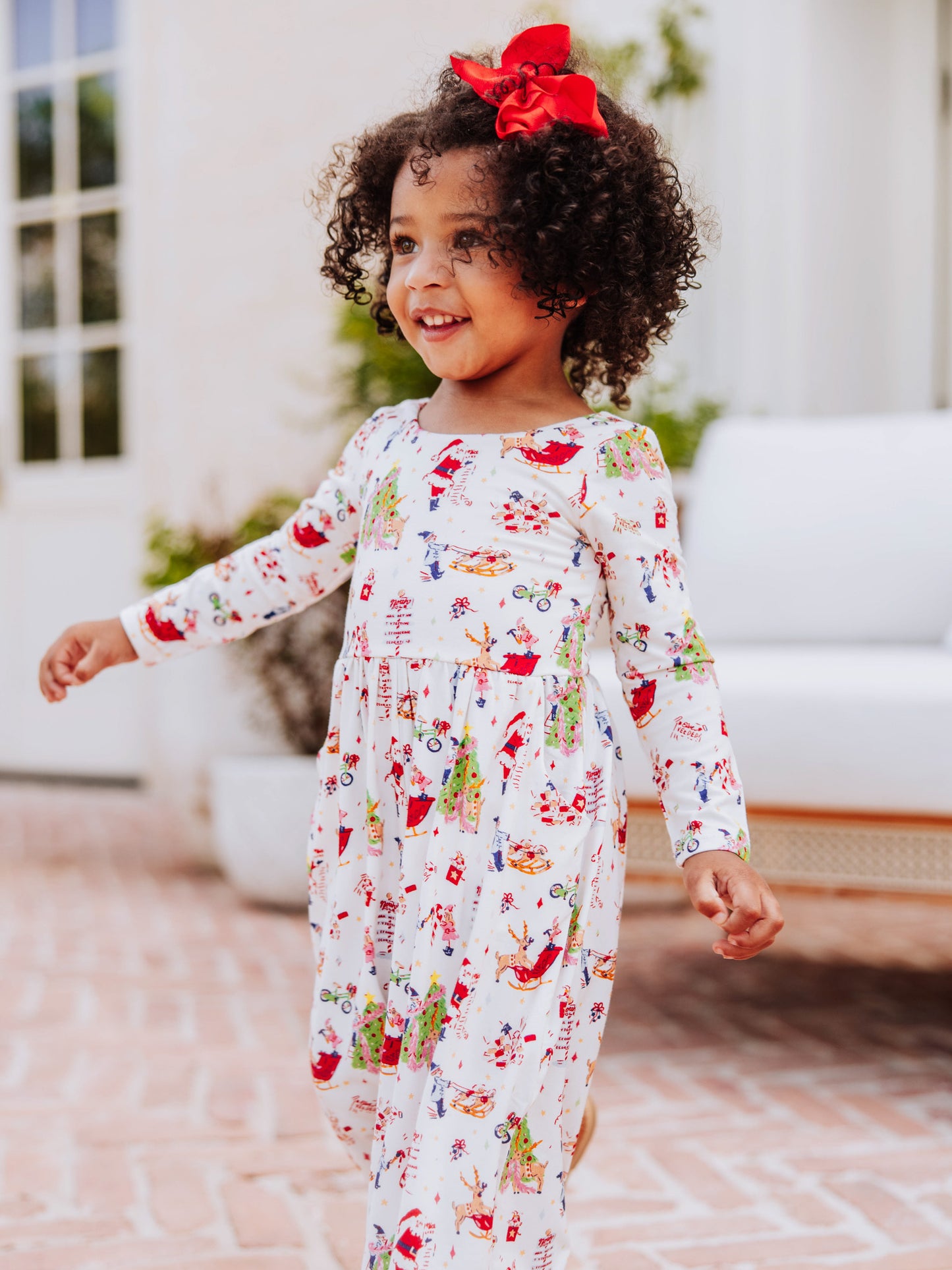 Model walking outside wearing a north pole printed leggy romper. 