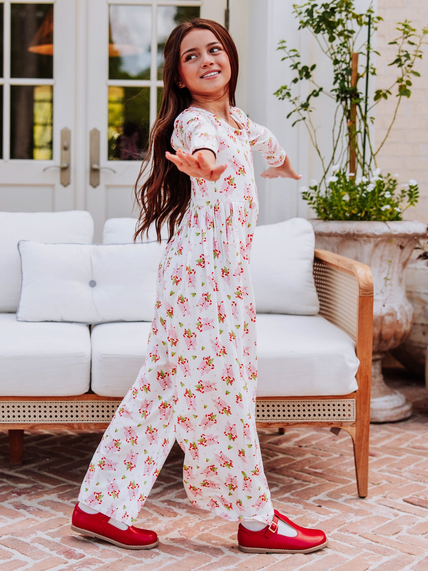 Model wearing a sweet candy cane printed leggy romper and is holding her arms out to the side. 