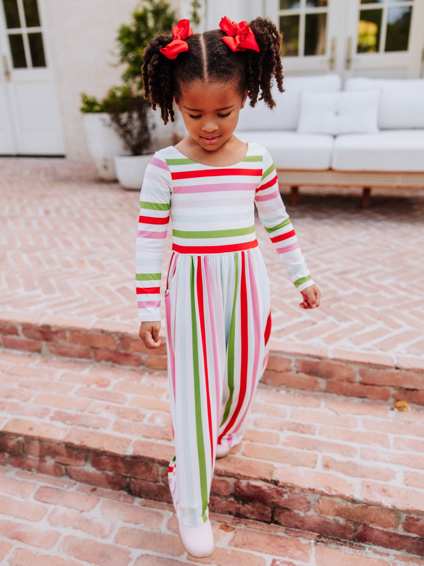 Model walking down steps in a multi-striped leggy romper.