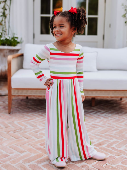Model with hand on hip wearing a striped leggy romper outside in front of white couch.