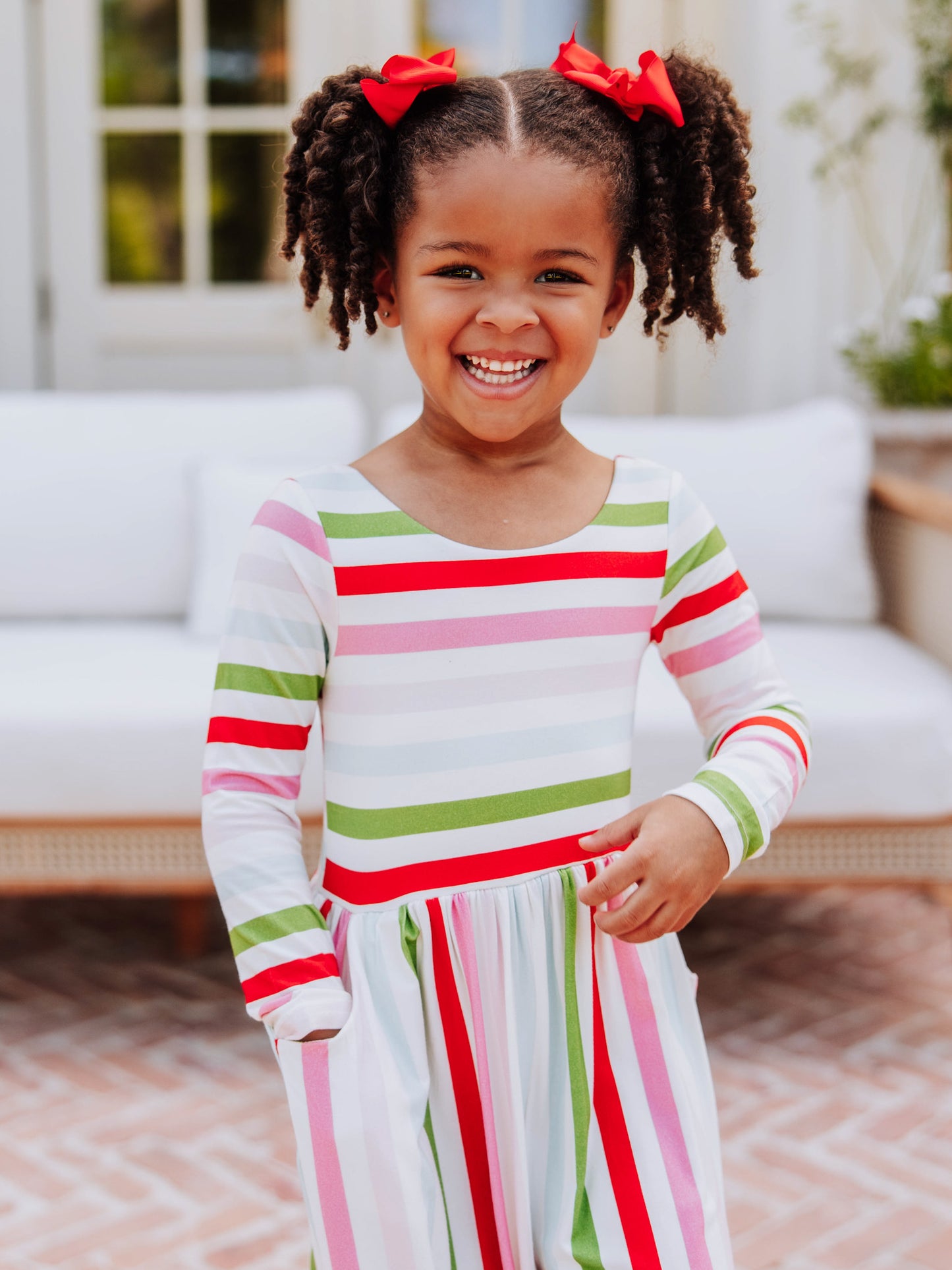 Little girl smiling wearing a different colored striped leggy romper