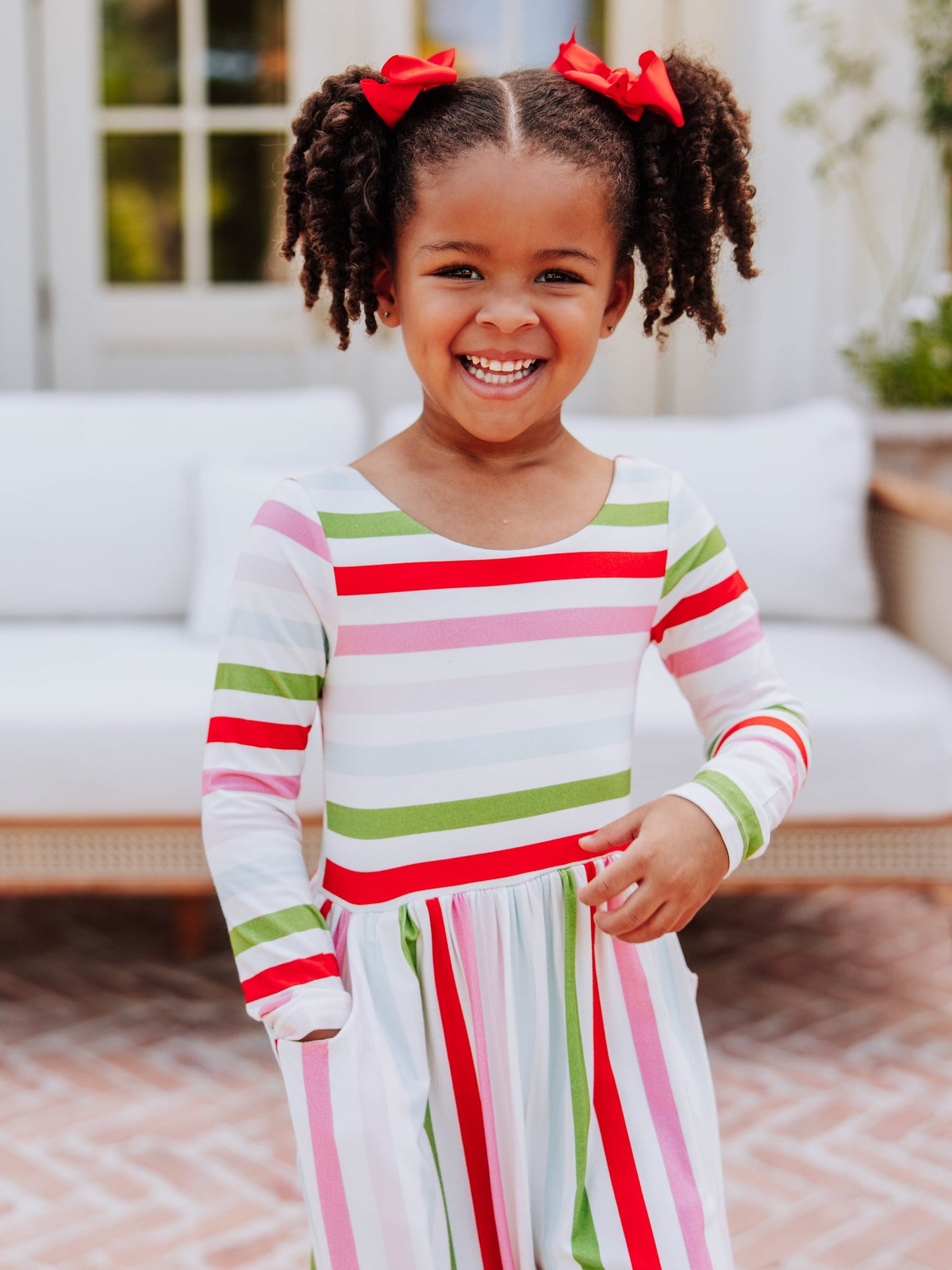 Little girl smiling wearing a different colored striped leggy romper