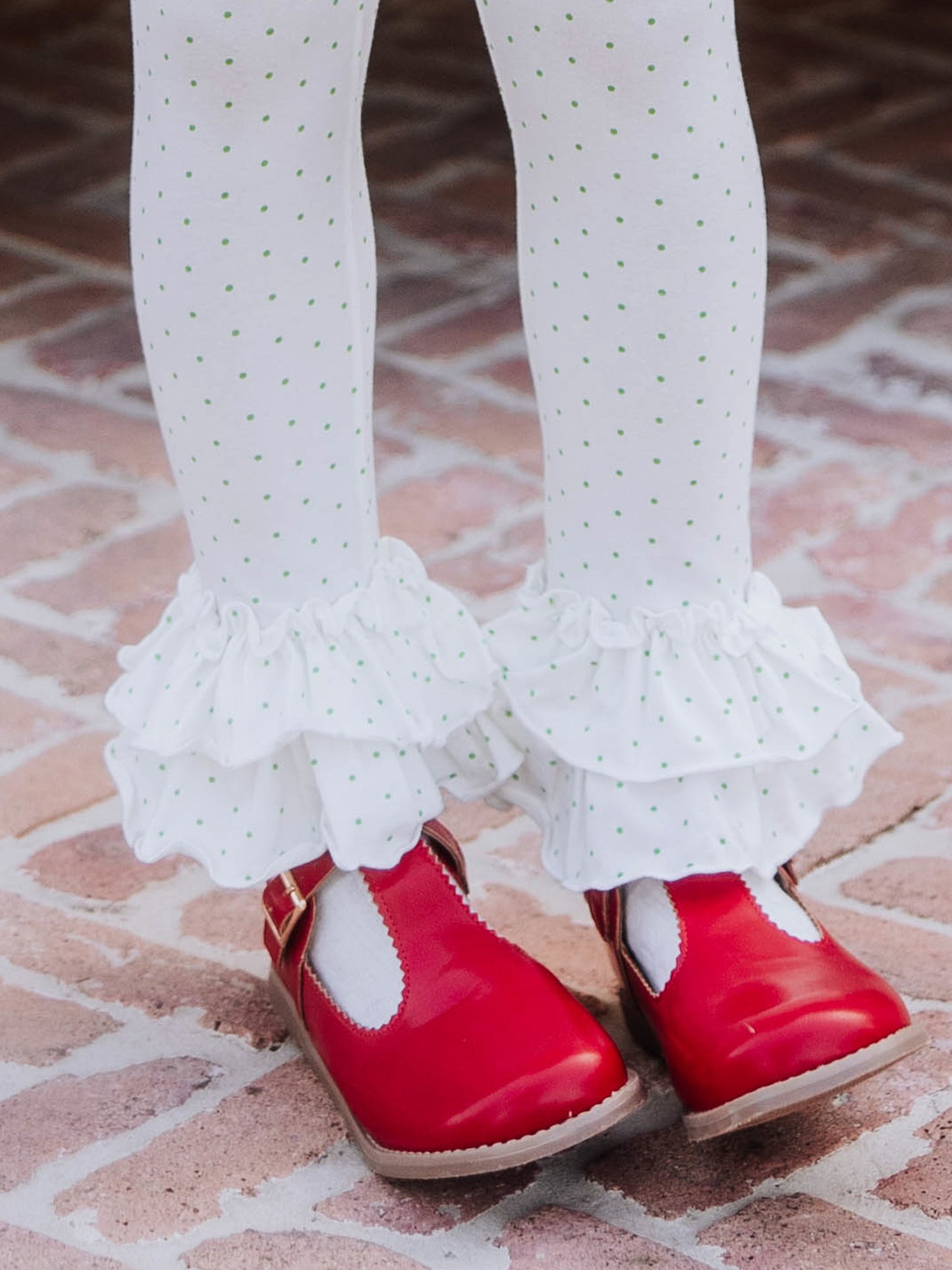 White tights with green polka dots and ruffles at bottom with red mary janes.