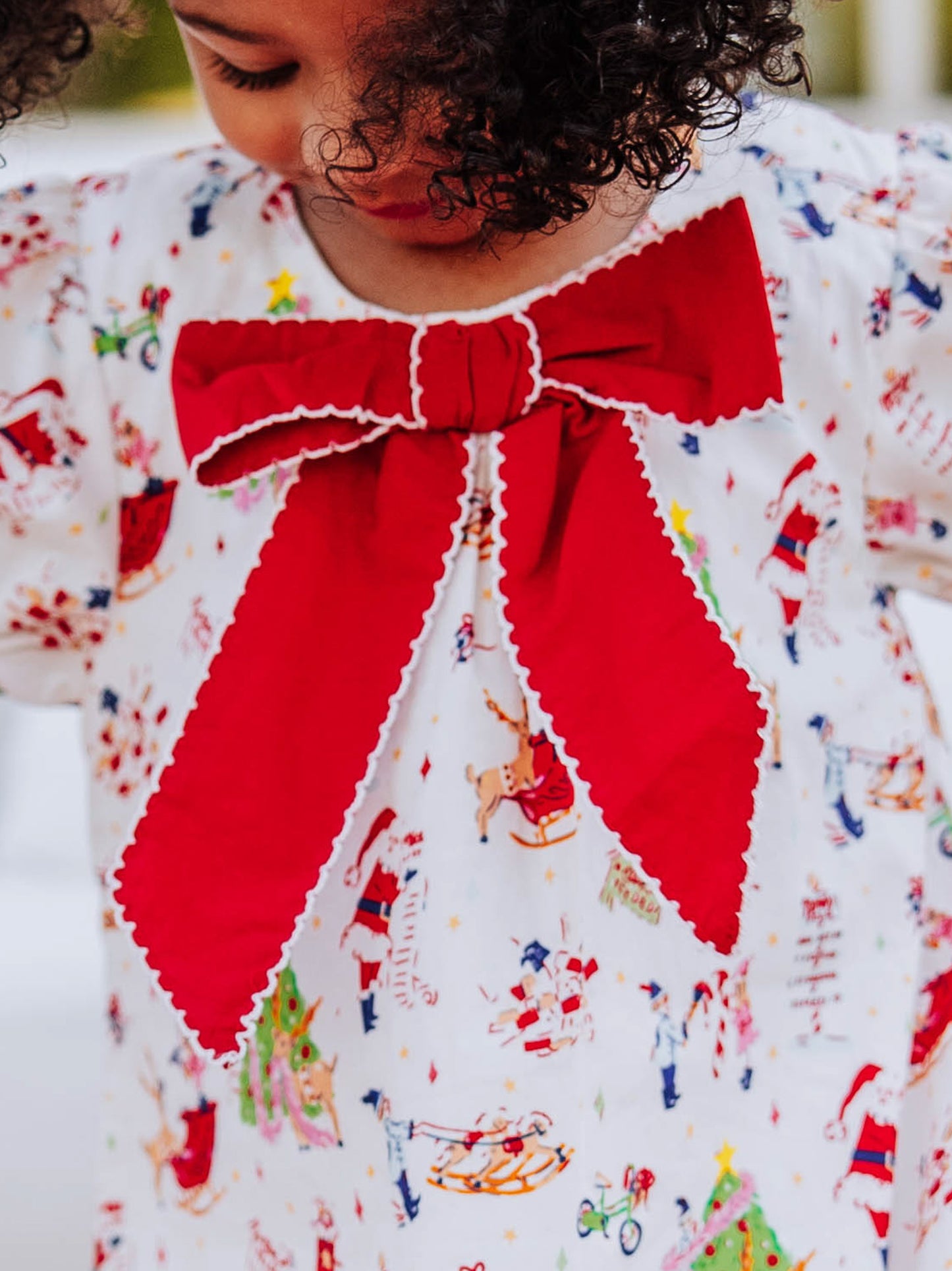 Close up of stitched red bow on Holiday printed dress.