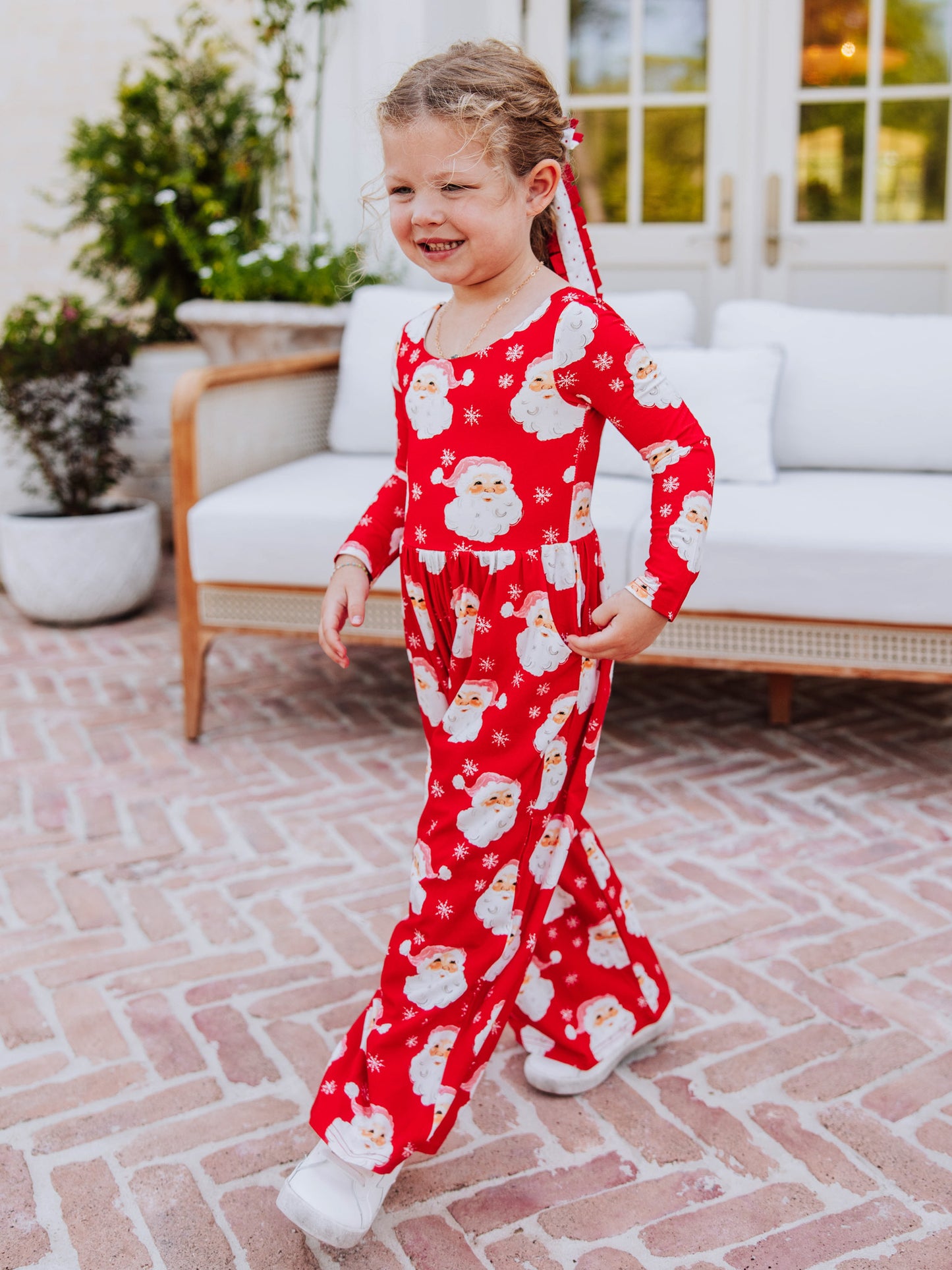 Girl wearing a red jolly santa leggy romper. 
