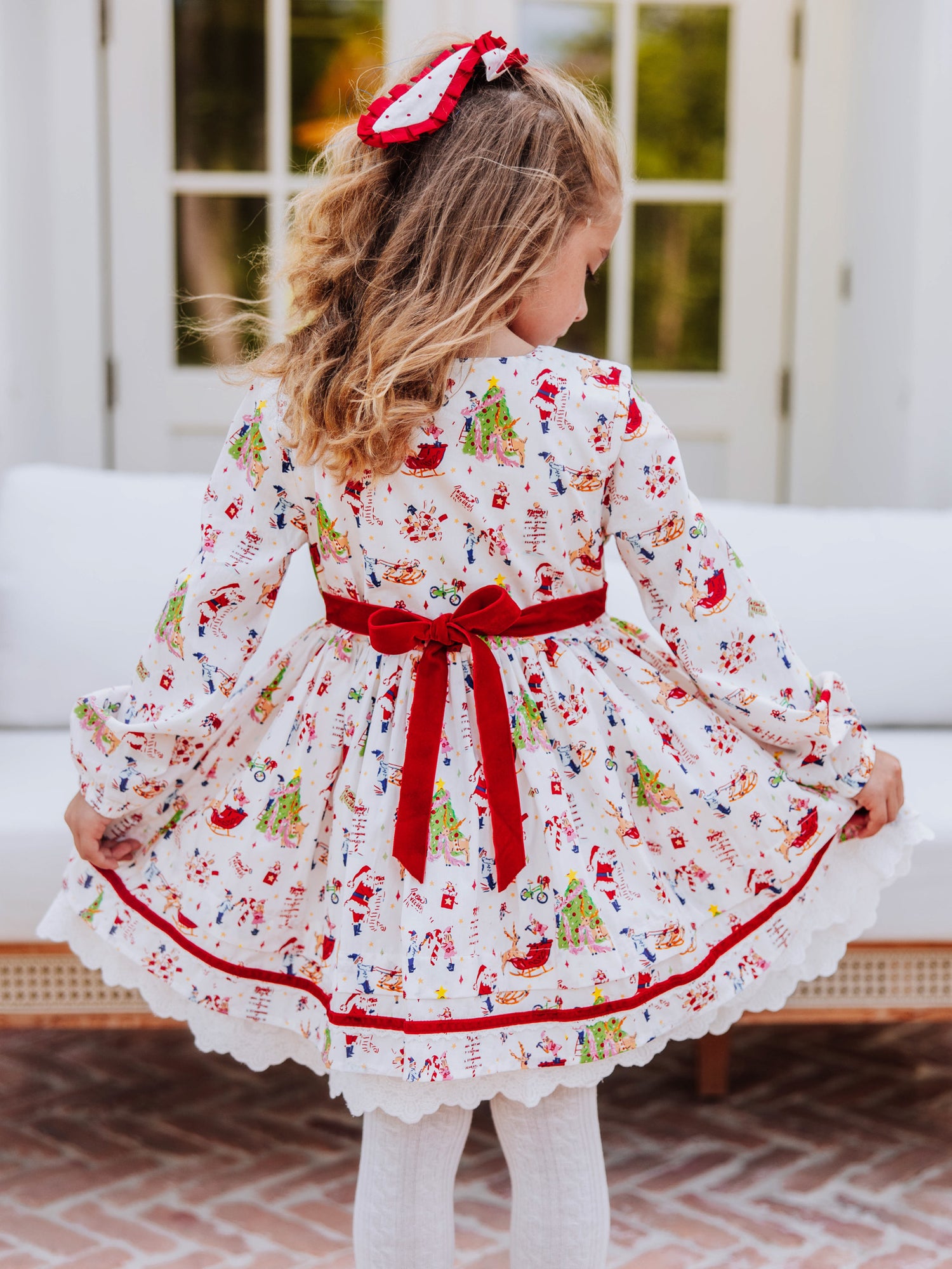 Backside shot of girl in holiday themed dress. Back shows velvet tie.