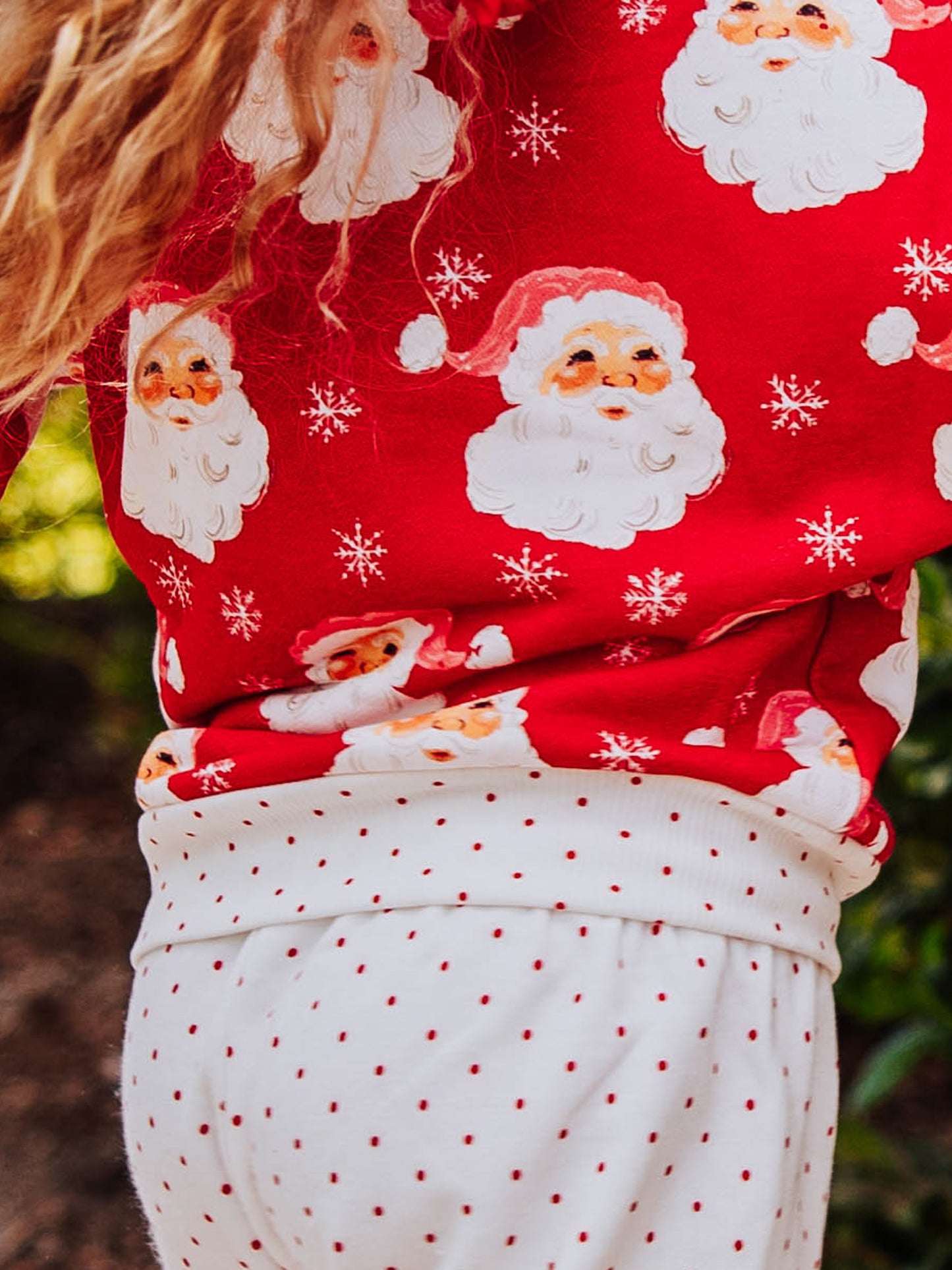 Girl outside wearing a jolly santa sweat set. 