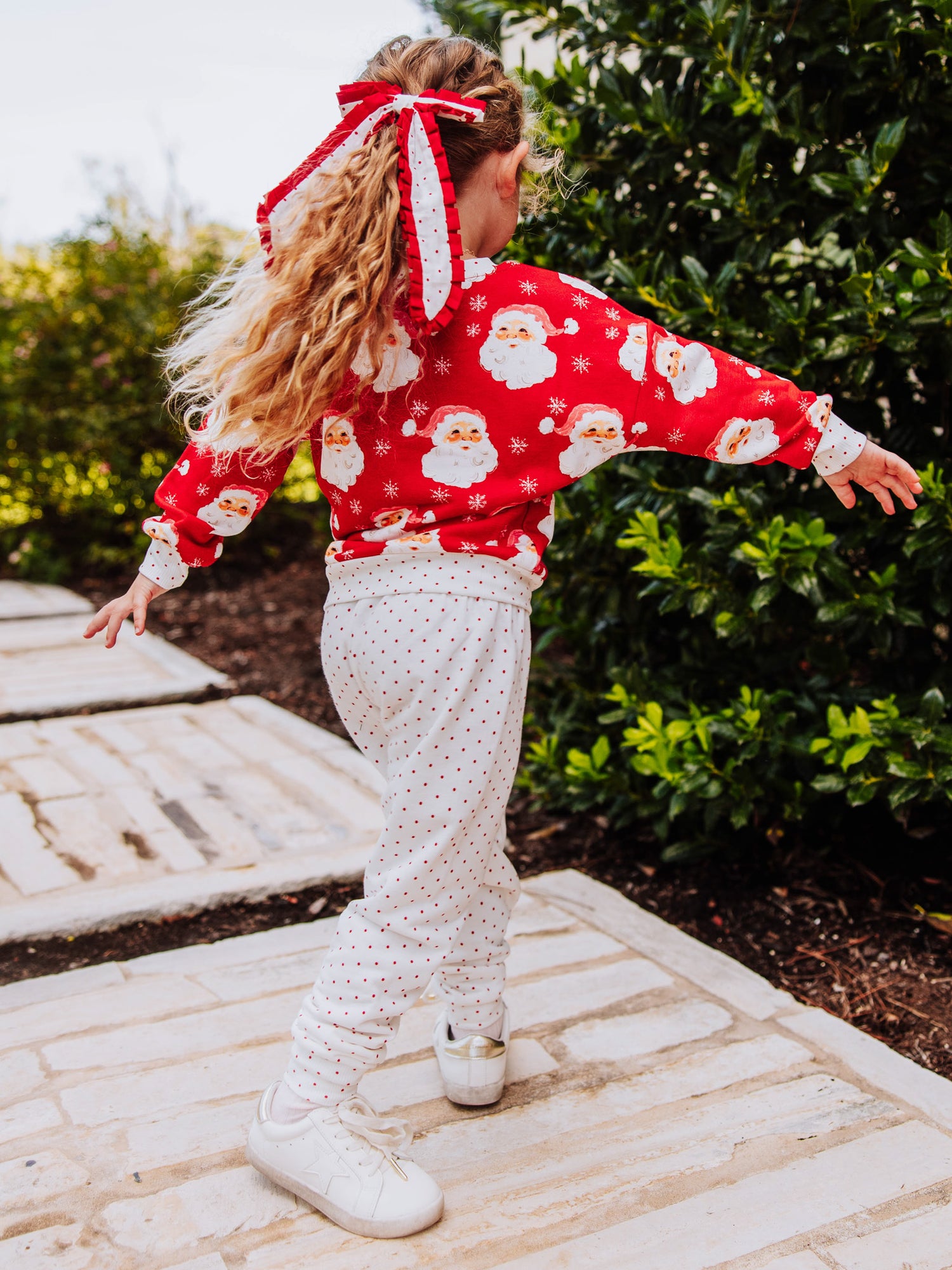 Girl outside wearing a jolly santa sweat set. 