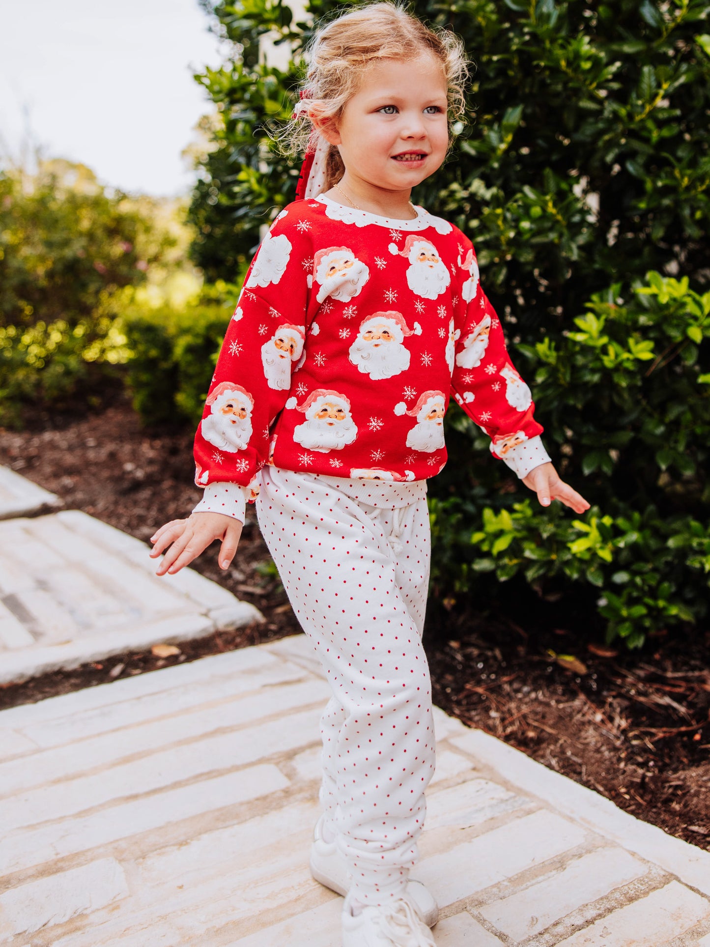 Girl outside wearing a jolly santa sweat set. 