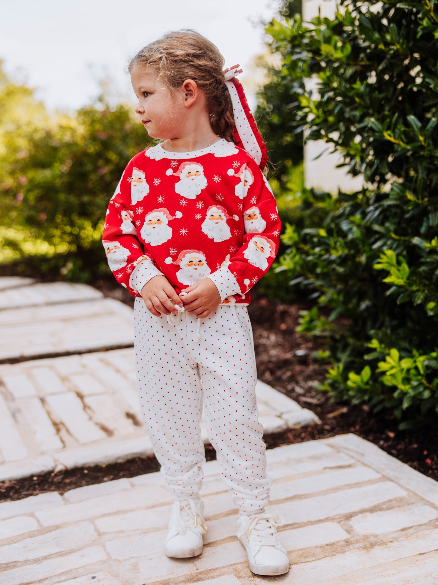 Girl outside wearing a jolly santa sweat set. 