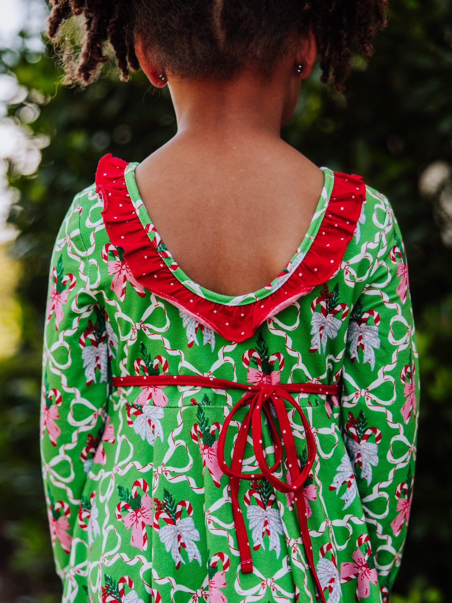 Back shot of the scoop back and ruffle detail on holiday patterned dress. 