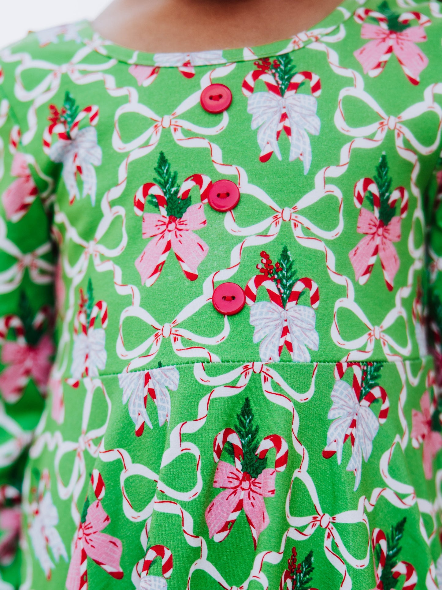 Up close picture of red accent buttons on bodice of holiday themed dress. 