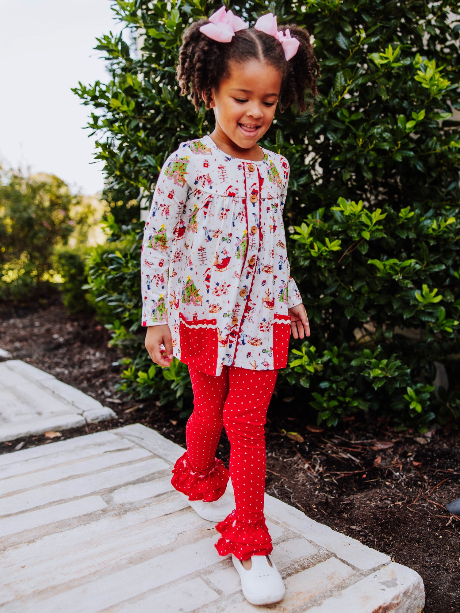 Girl wearing a Holiday themed top with red leggings with white polka dots. This set is an out to play set. 