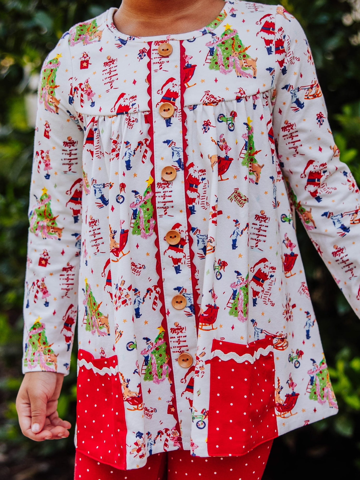 Girl wearing a Holiday themed top with red leggings with white polka dots. This set is an out to play set. 