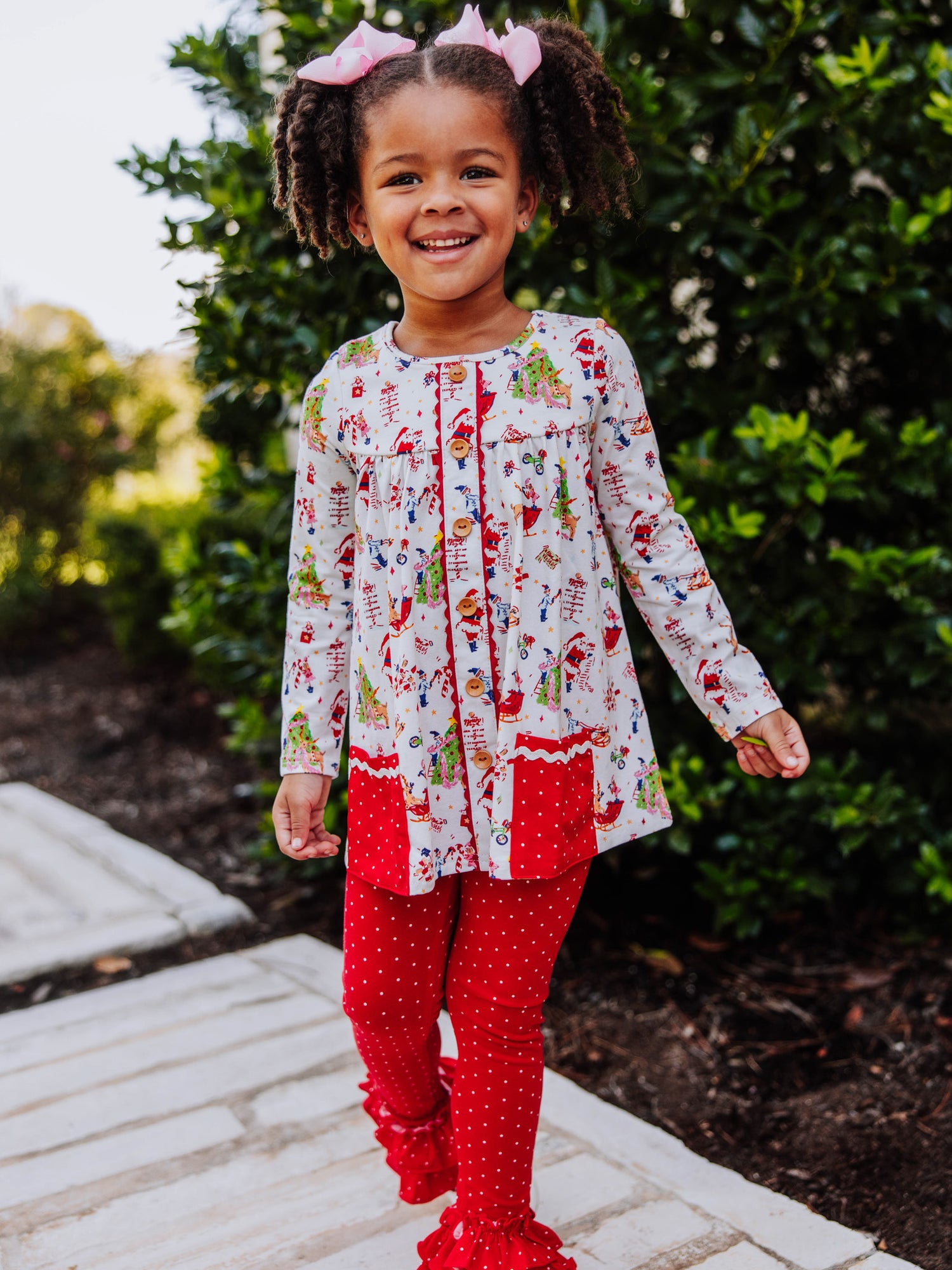 Girl wearing a Holiday themed top with red leggings with white polka dots. This set is an out to play set. 