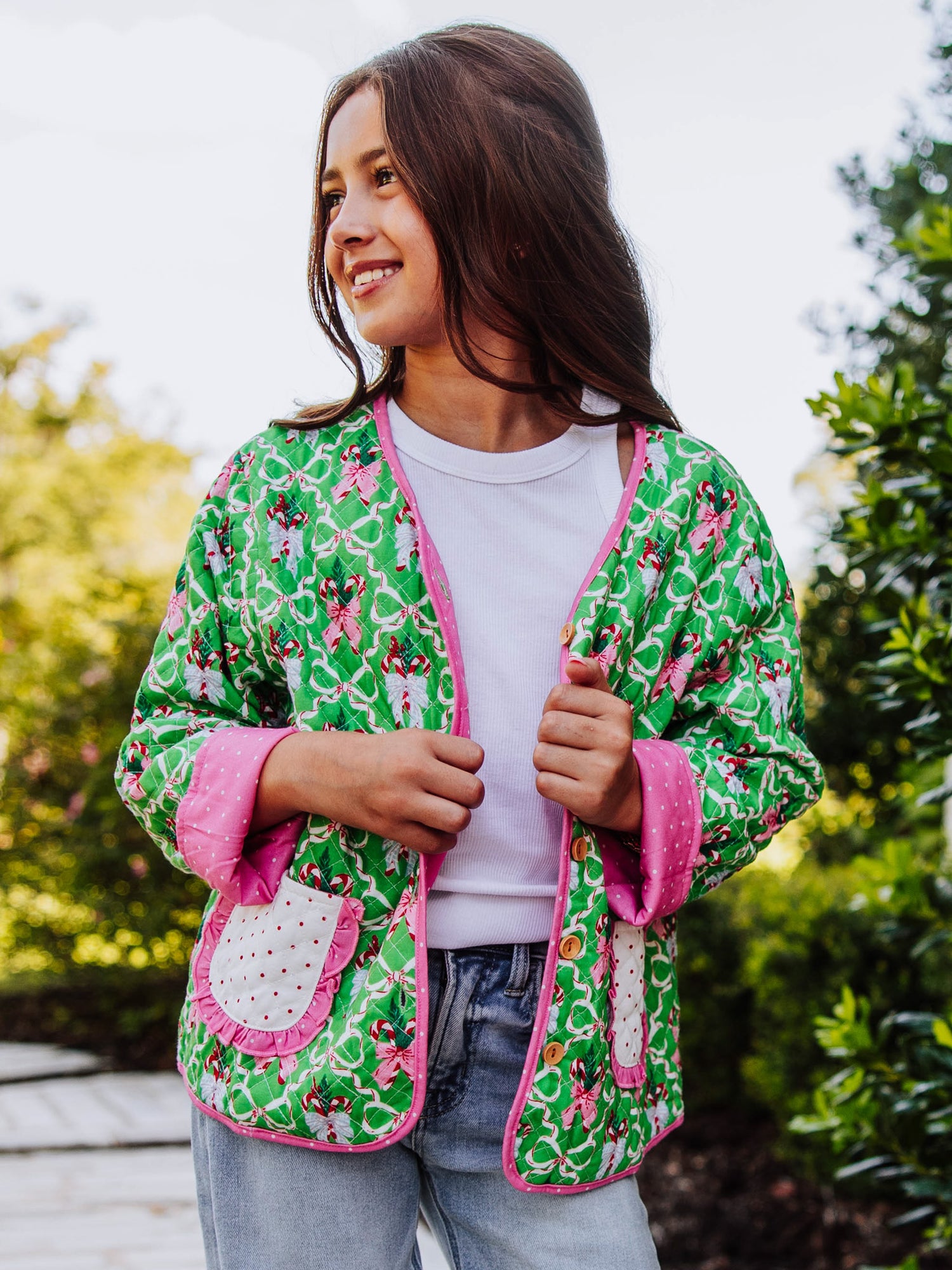 Girl wearing a quilted holiday themed cardigan with a white shirt underneath and jeans. 