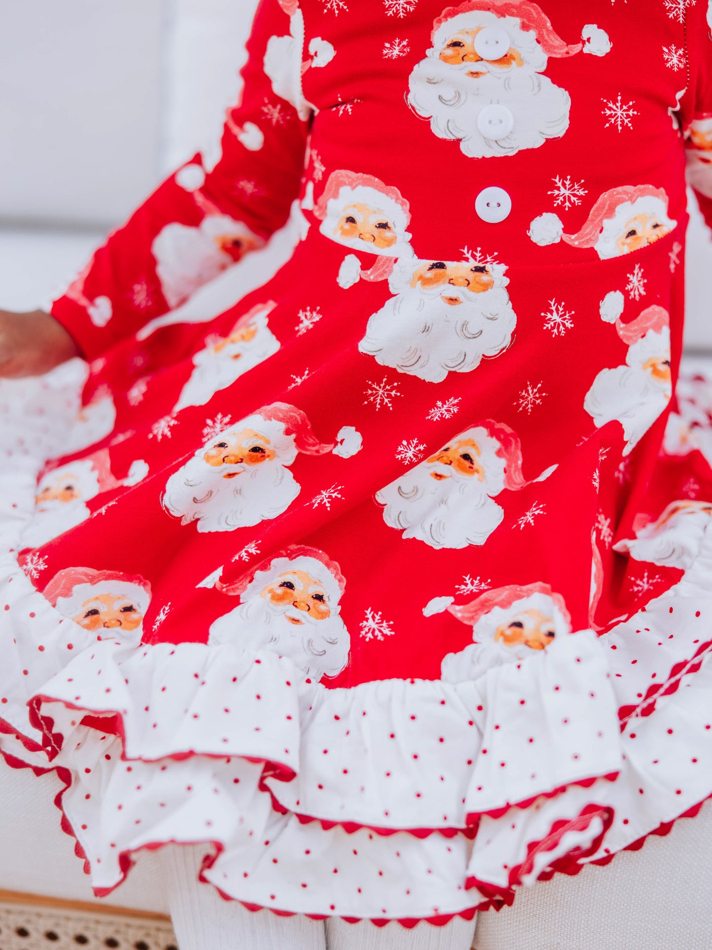 Up close picture of red santa print on dress with ric rac trim detail at hem.