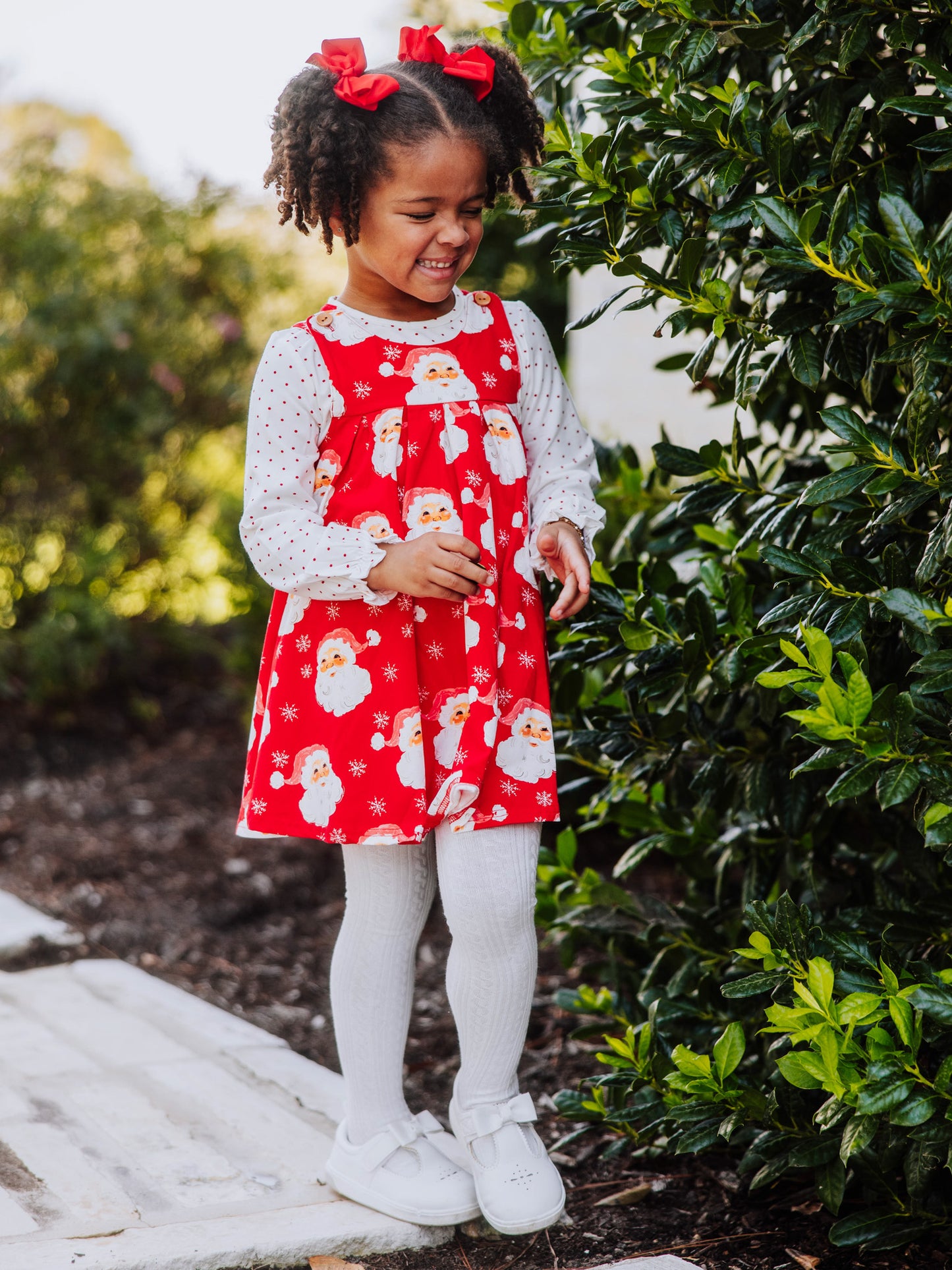 Girl outside wearing a holiday themed retro jumper with white tights and white shoes. 