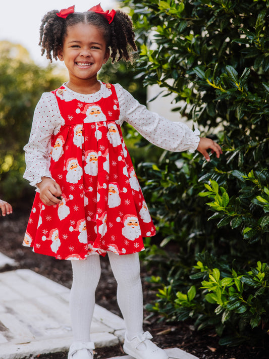 Girl wearing a holiday themed jumper with white tights and white shoes. 