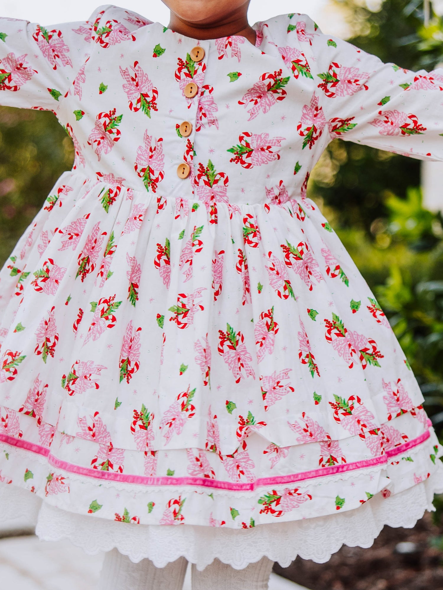Up close shot of the print on model's dress. It's pink candy canes with buttons on bodice. 