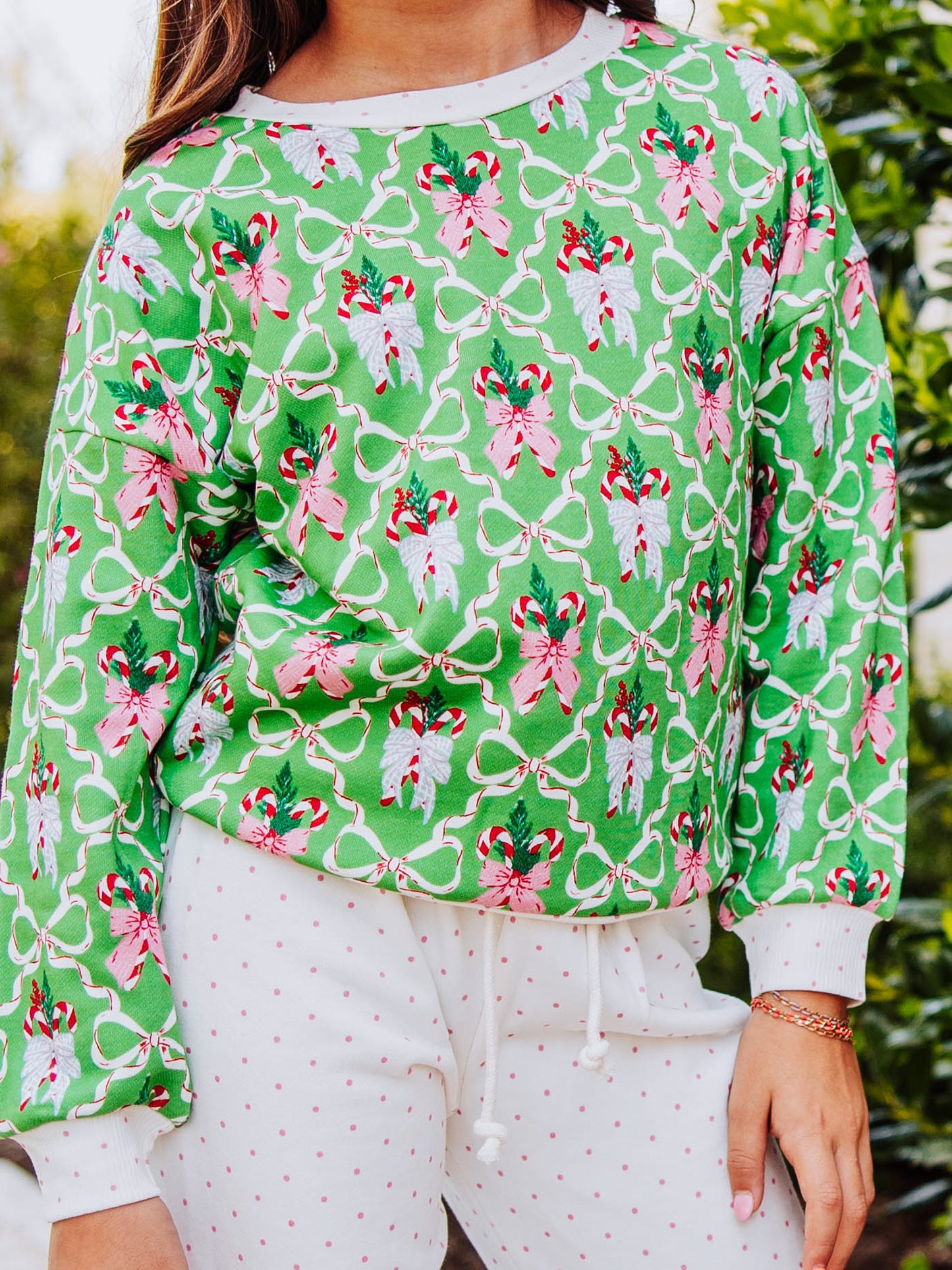 Up close pic of holiday themed sweatshirt. Green with bows and candy canes.