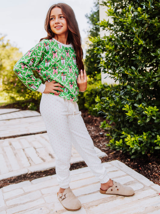 Girl standing outside with hands on hips wearing a holiday themed sweat set with tan clogs. 