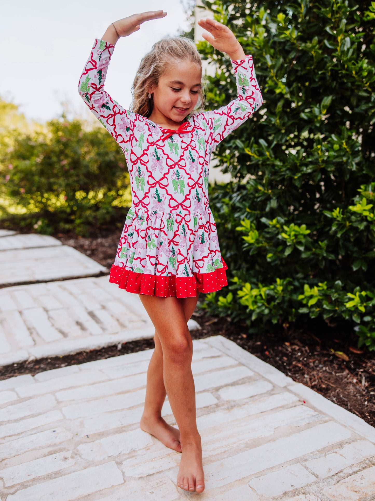 Girl wearing a holiday themed skirted leotard posing in a ballet move. 