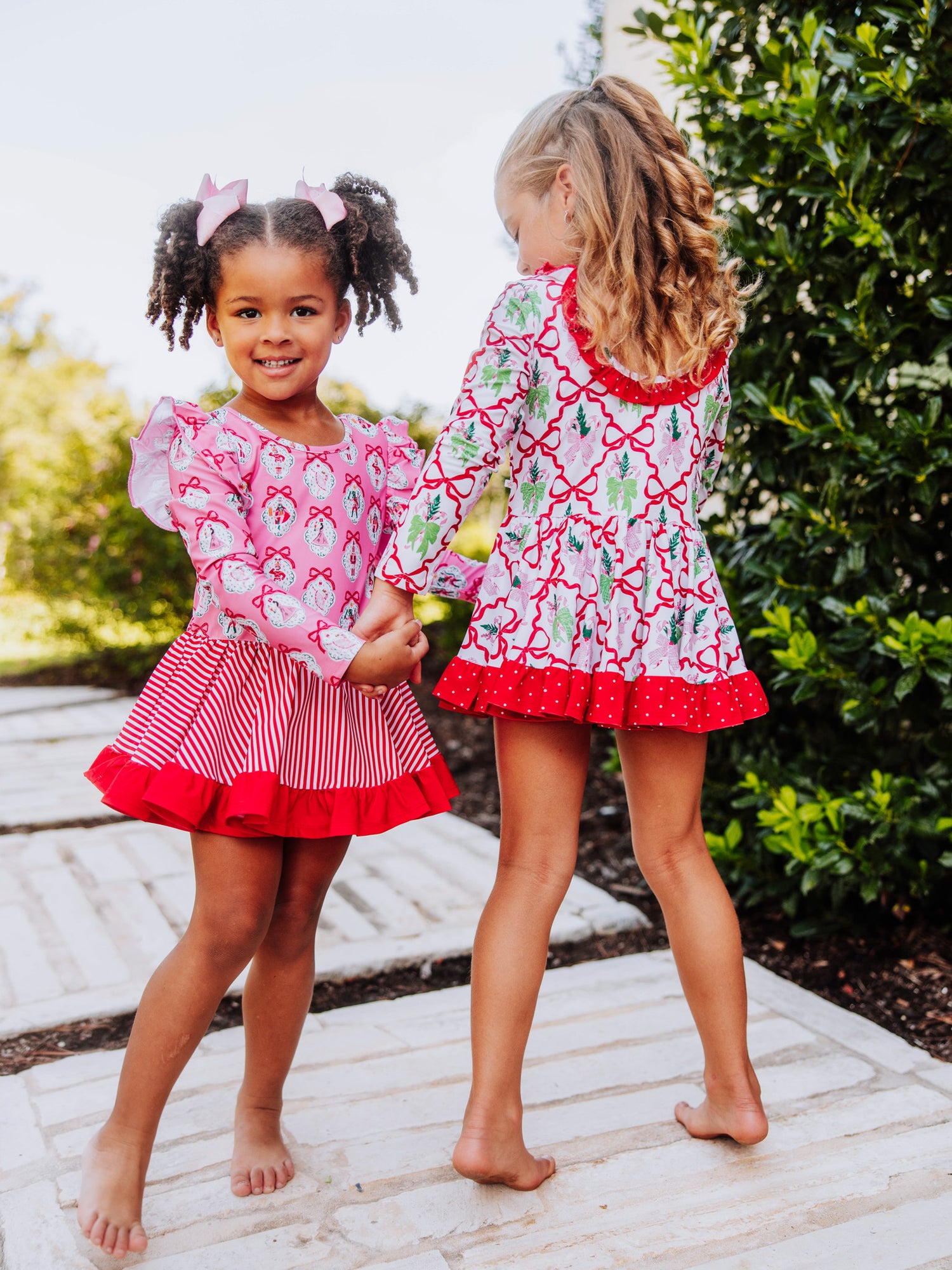 Two girls holding hands and both are wearing holiday themed skirted leotards. 