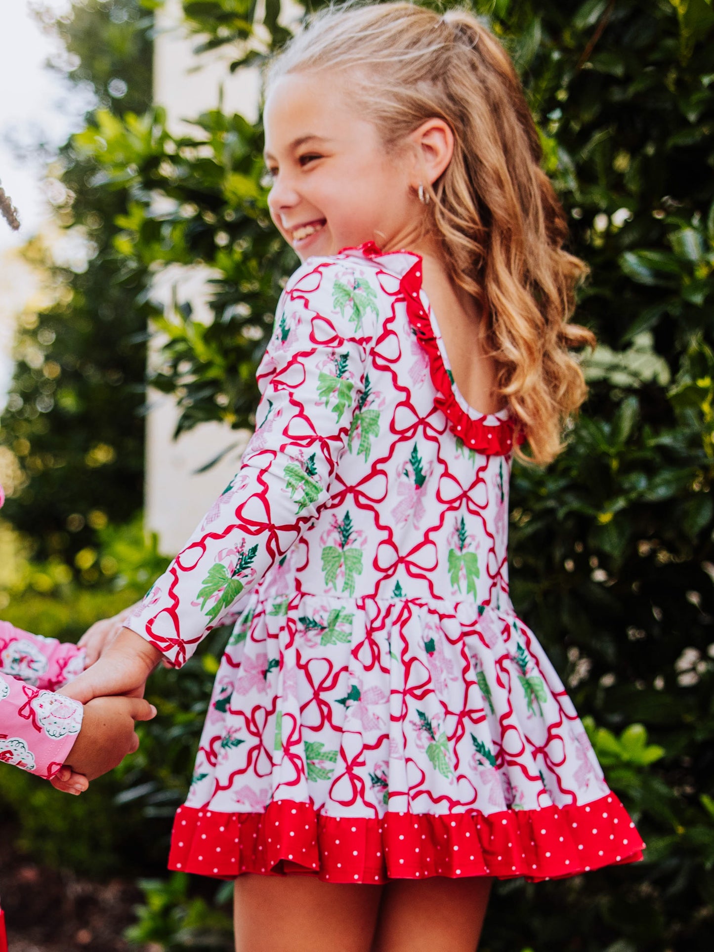 Model wearing a holiday themed skirted leotard smiling. Picture is showing the back of leotard details. 