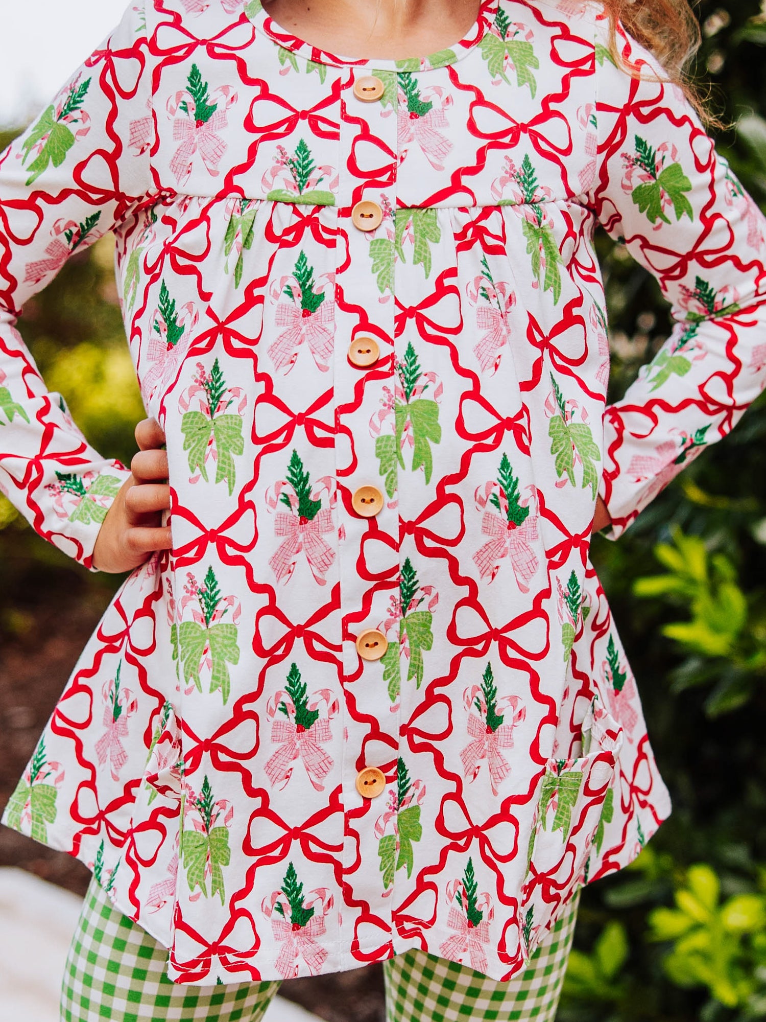 Holiday bow themed top with wooden buttons going down. Bottoms are green gingham. 
