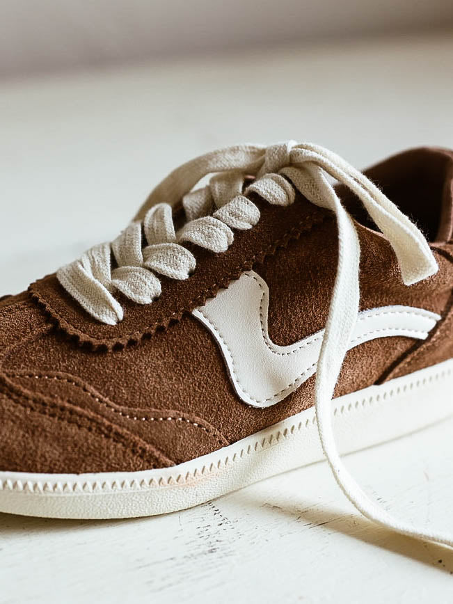 Brown mocha colored suede sneakers with a swish design on the side in a creamy white and creamy white laces.