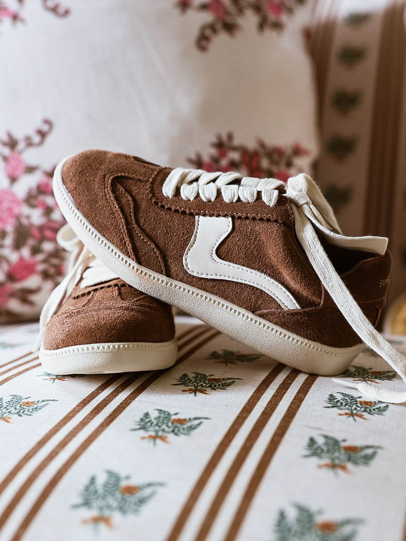 Brown mocha colored suede sneakers with a swish design on the side in a creamy white and creamy white laces.