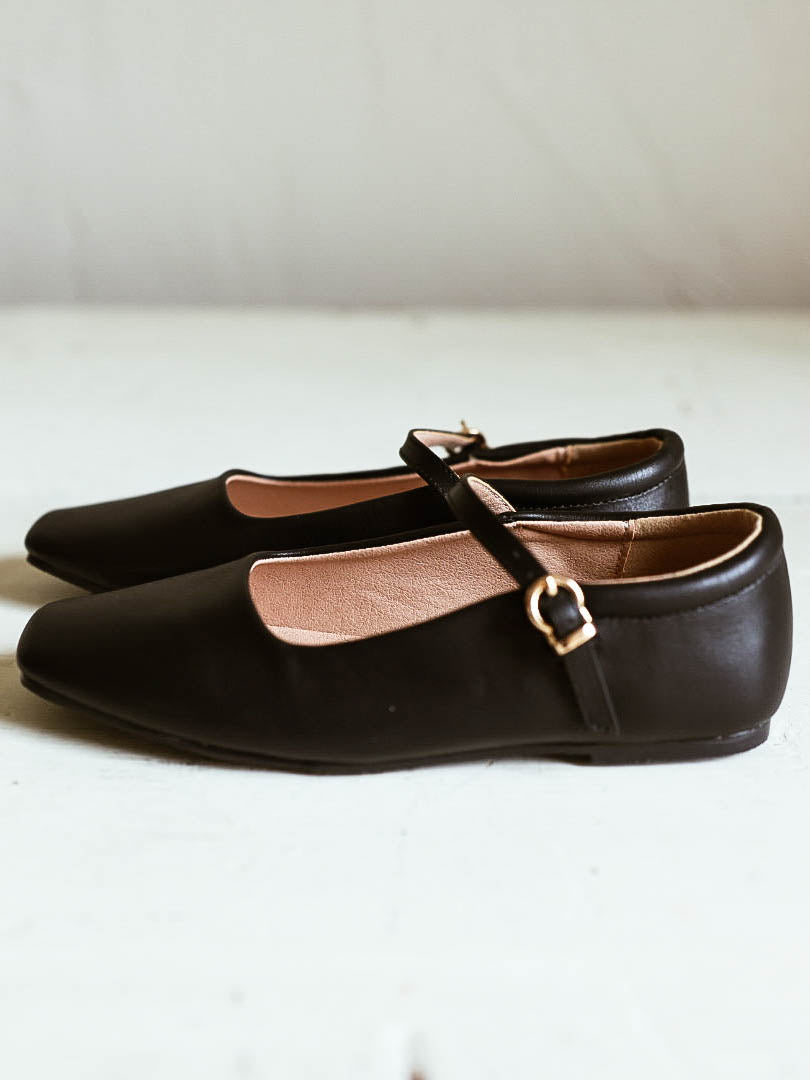 Picture of black ballet mary janes with square toe and a clasp buckle closure. White background