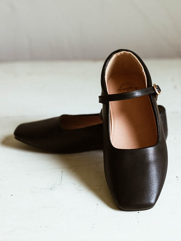 Picture of black ballet mary janes with square toe and a clasp buckle closure. White background