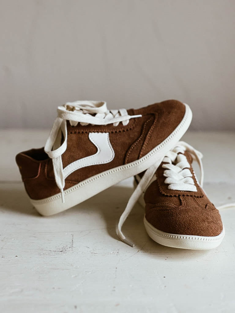 Brown mocha colored suede sneakers with a swish design on the side in a creamy white and creamy white laces.